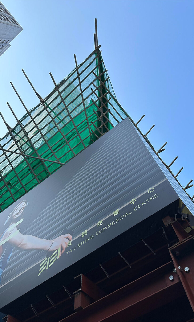 A low-angle shot of the Yau Shing commercial centre, some construction work is in progress on the rooftop, by Studio X