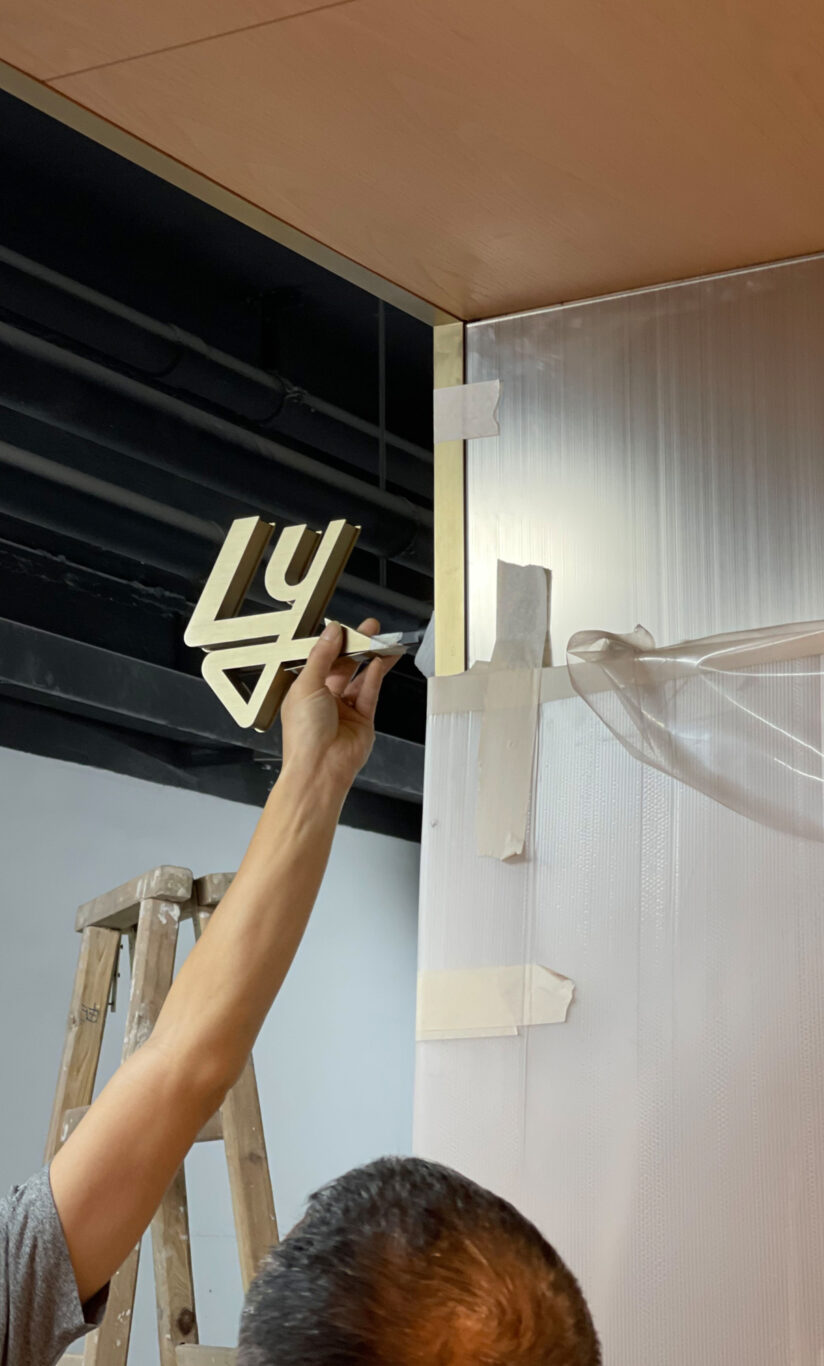 A man mounting a decorative piece inside the Lee Yuen Houseware store, a retail design project by Studio X