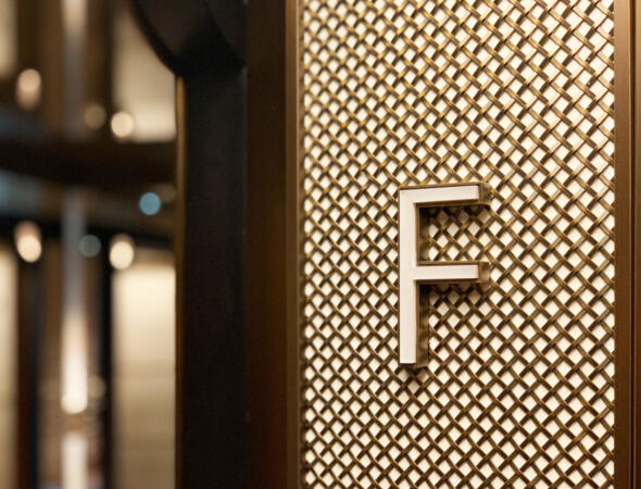 A fancy luxurious corner inside a building displays an alphabet "F" sign, made of aluminum, a Studio X project