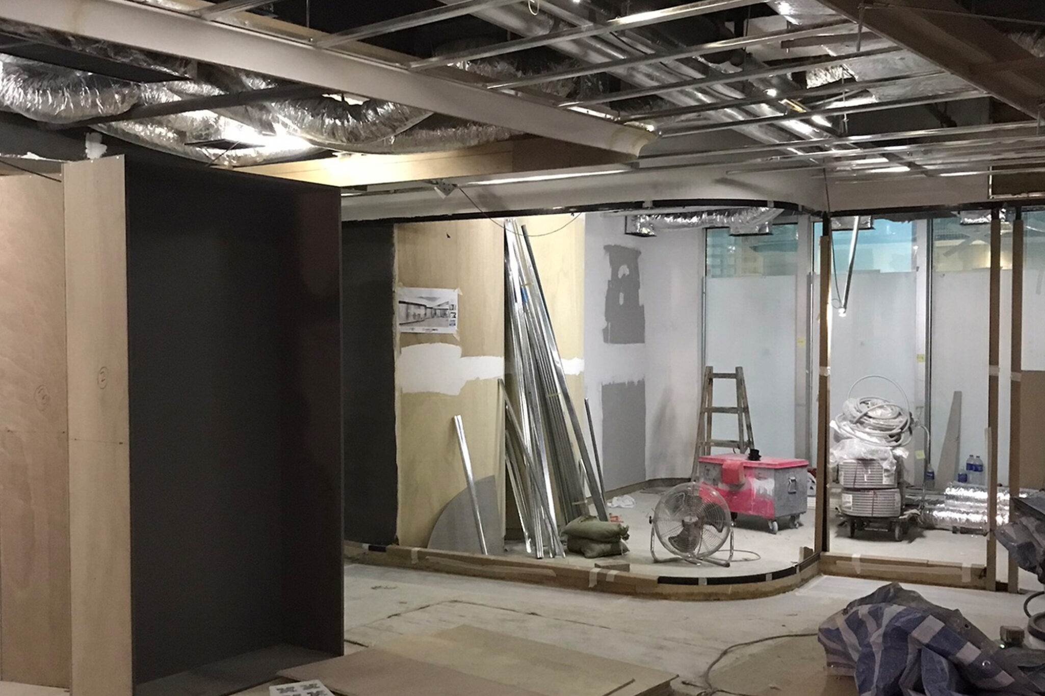 A wide-angle shot of a construction site in a plaza, showing painting and finishing work in progress, a project by Studio X