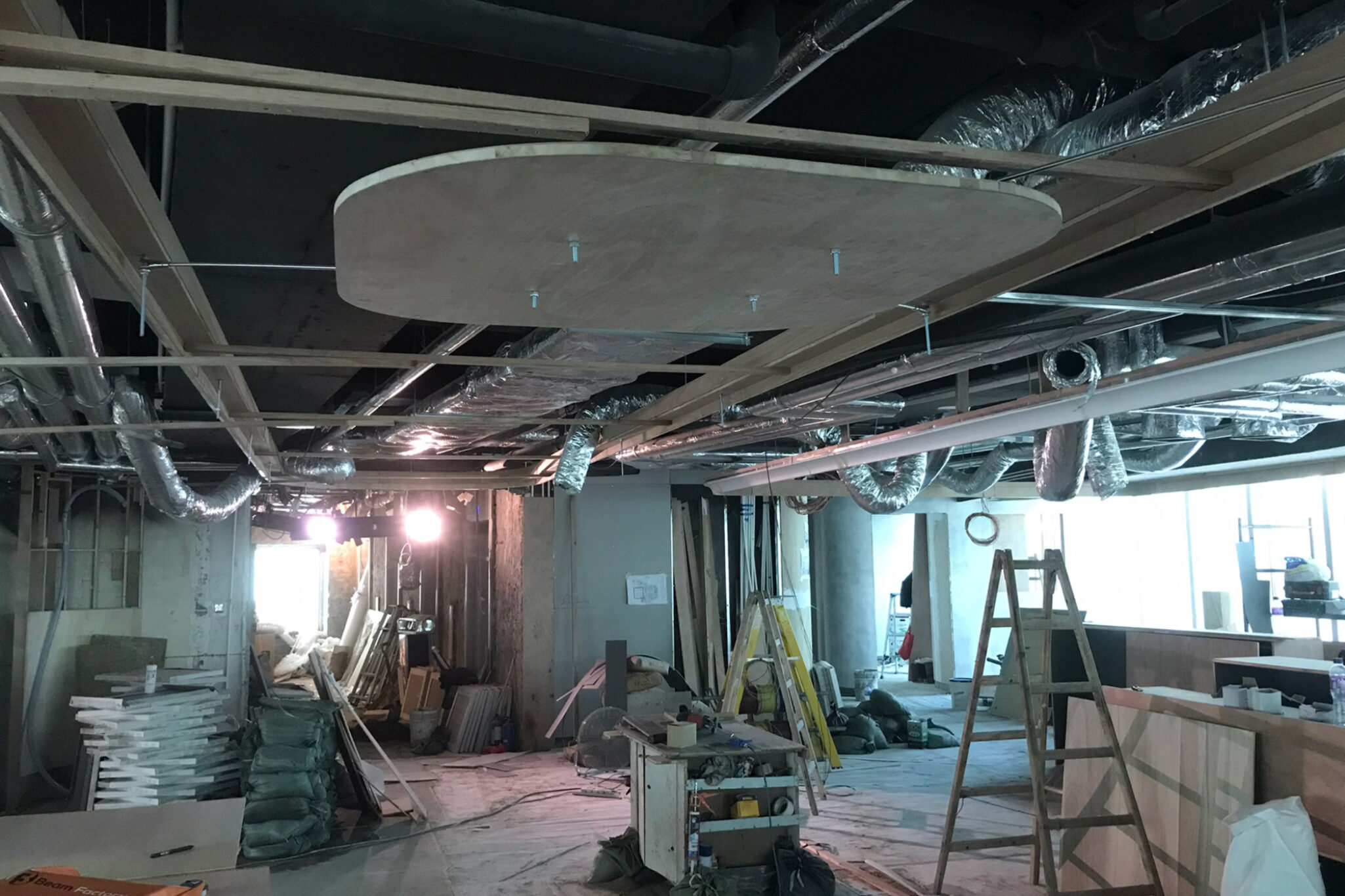 A wide-angle shot of an indoor construction site showing various tools and ceiling work in progress, a Studio X project