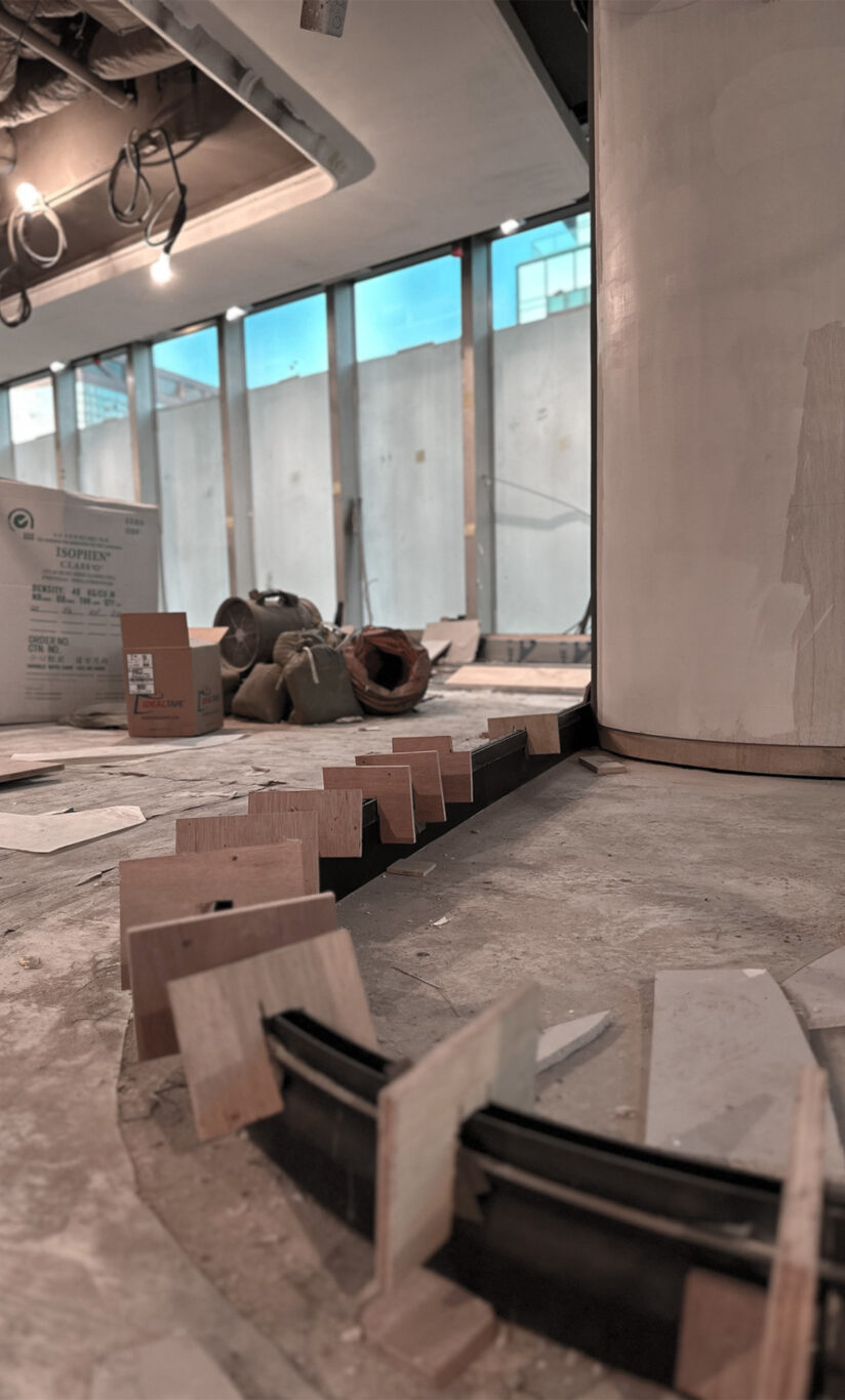 A construction site where flooring work appears to be in progress, with finished ceilings and walls - a project of Studio X