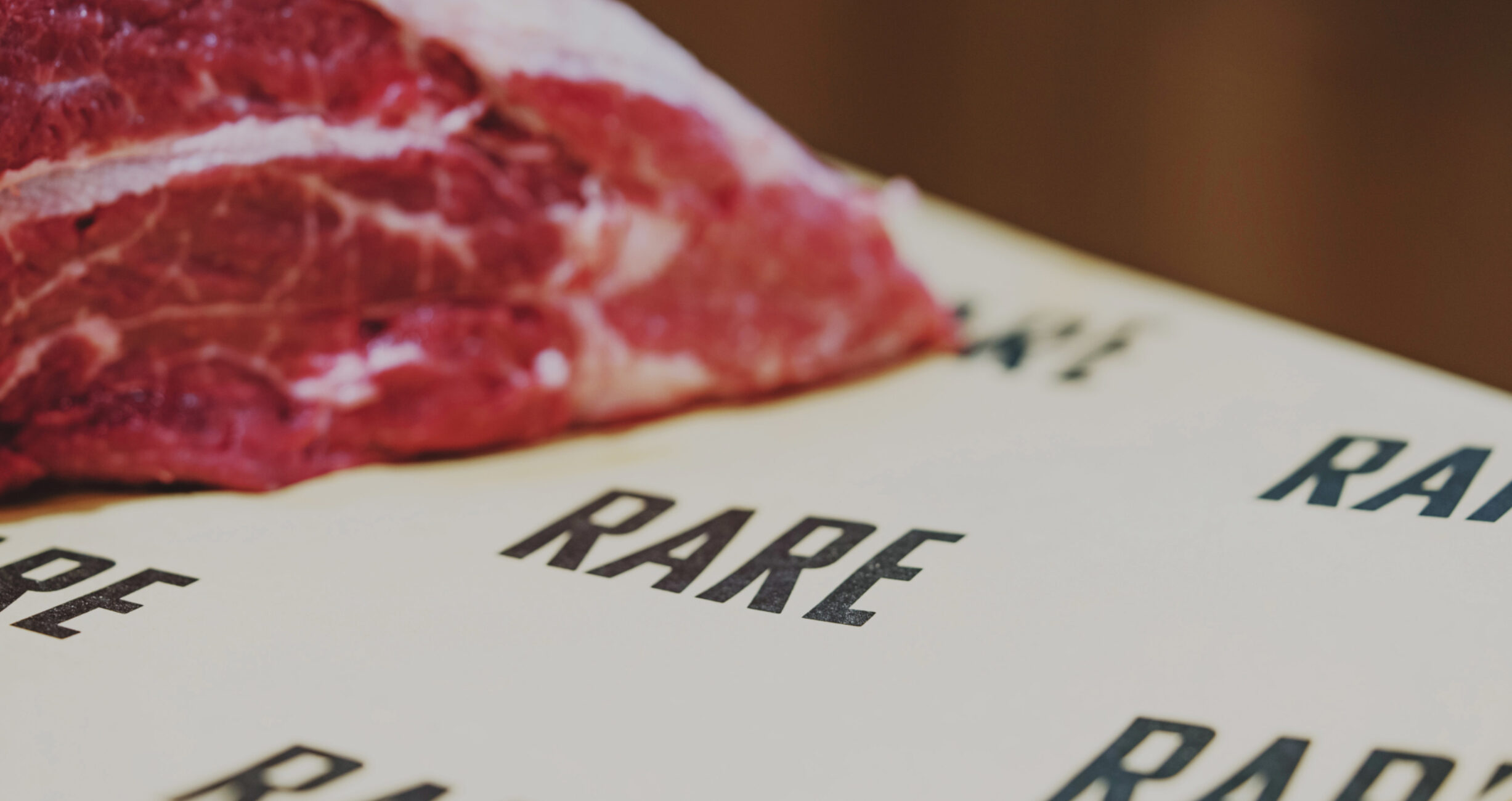 A closeup shot of a food wrapping paper with the branding of "RARE", and some cow meet on the other side, Studio X