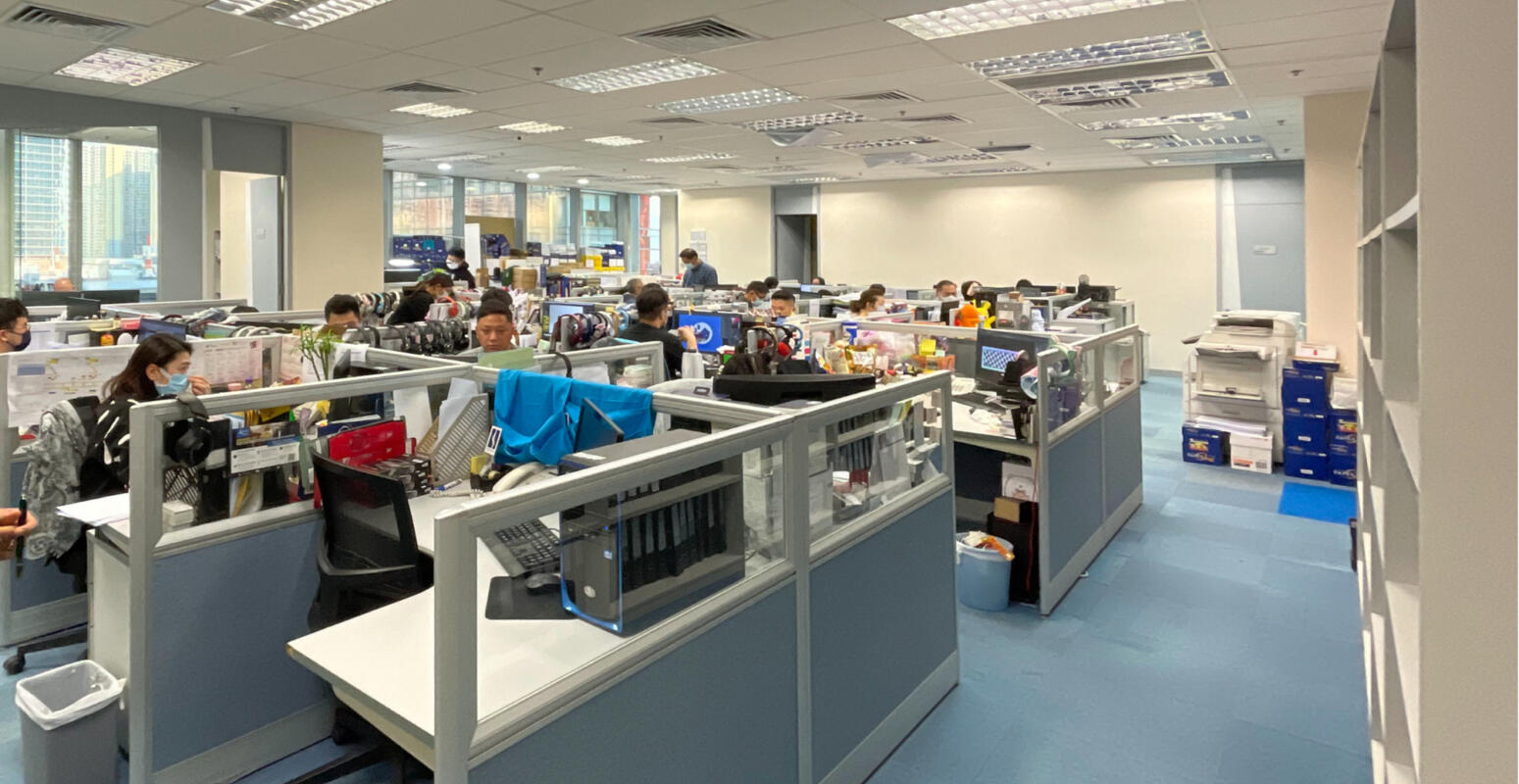 A wide-angle shot of a cluttered corporate office workplace with many people working, before Studio X's redesign