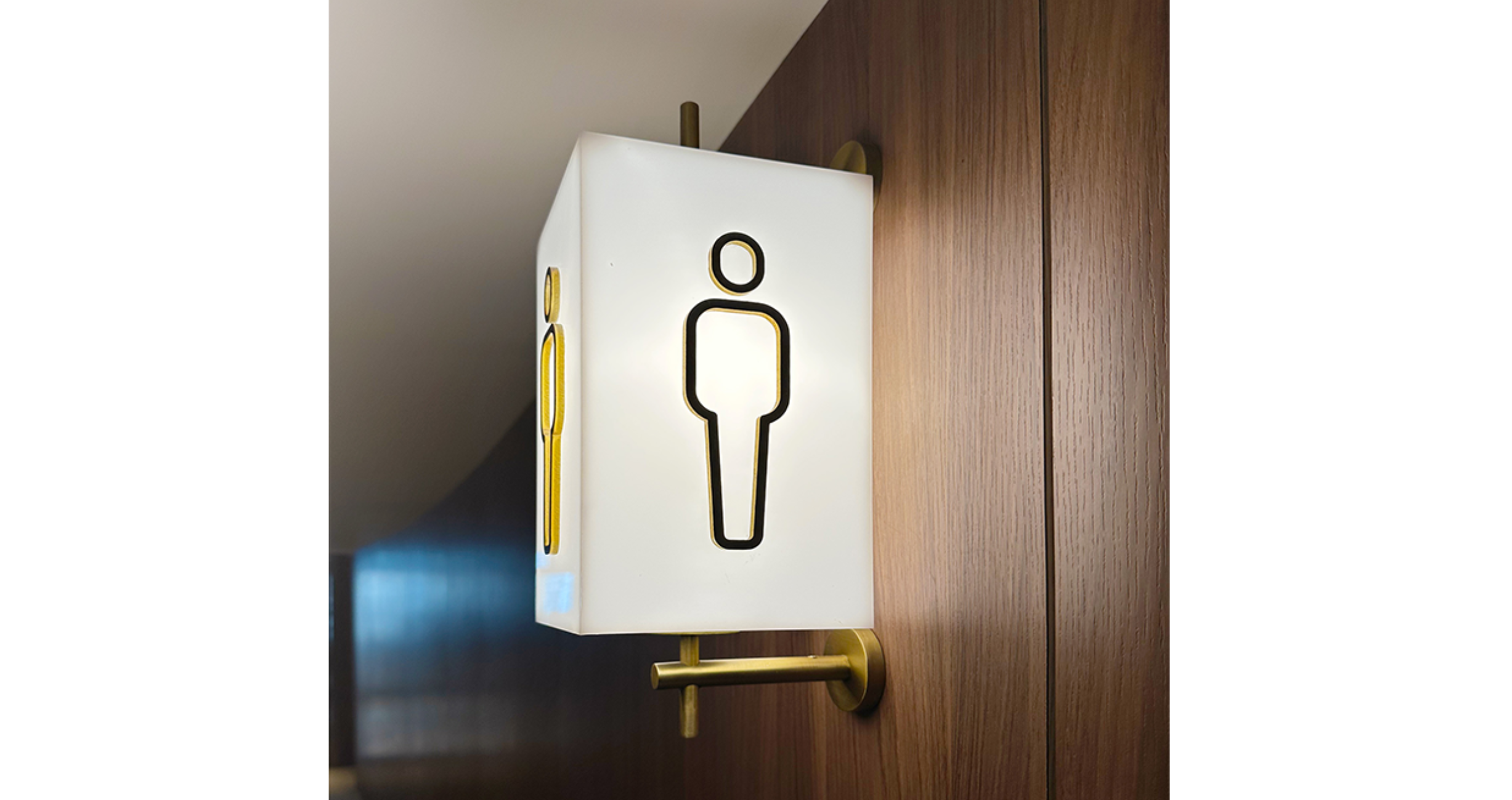 A decorative fancy lamp mounted on the wall with a men's toilet signage, a design project by the Studio X